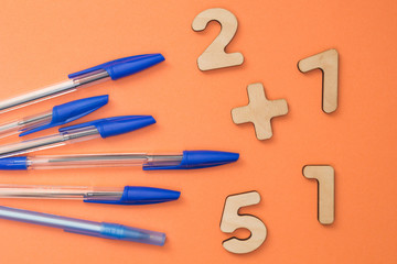 School accessories, blue pens on an orange background. Mathematical numbers for children.