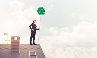 Businessman in suit on house top with ecology concept signboard.