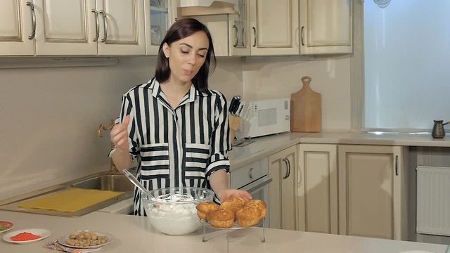 Young woman in the kitchen whipping with a white cream mixer in a transparent dish