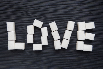 Word Love from sugar cubes on black background
