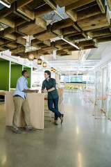 Two co-workers meeting in common area of modern office space