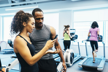 Man and woman looking at a cell phone in the gym 