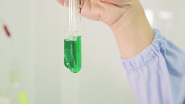 Close-up of a woman hand lab assistant with a test tube. Female scientist working on tablet computer and checking test tubes in lab