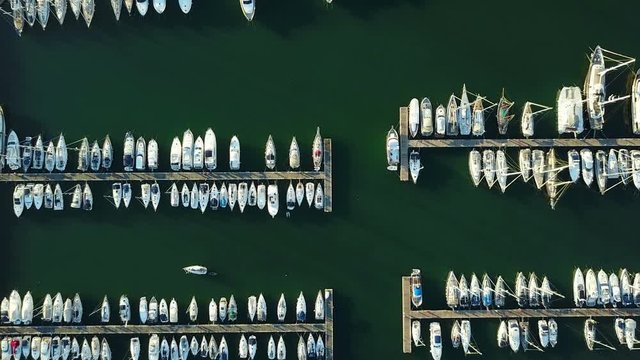 4K. Flight over marina with moored yachts and ships, aerial bird's eye view at sunset.