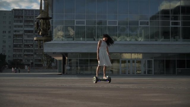 Girl posing on hoverboard at street