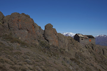 Derelict mountain hut, Refugio Alemana, in the mountainous landscape of Parque Yerba Loca set in a glacial valley close to Santiago, capital of Chile. Santiago in the distance under a layer of smog.