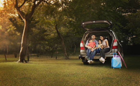 Family Sitting Together In Back Of Car With Open Hatchback At Picnic	