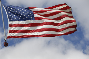Fototapeta premium American flag flying under the blue sky and clouds