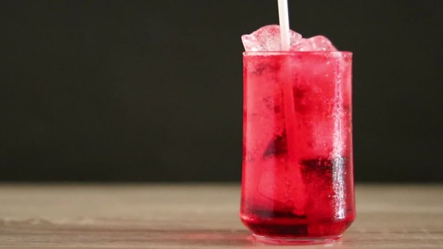 Drinking cold coca water with a white tube on wooden table and black background.