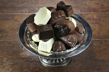 Belgian chocolate pralines in a silver bowl  on rustic wooden background