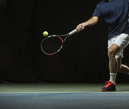Close up photo of a man swinging a tennis racquet during a tennis match
