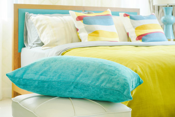 Closeup green pillow with colorful bedding in background