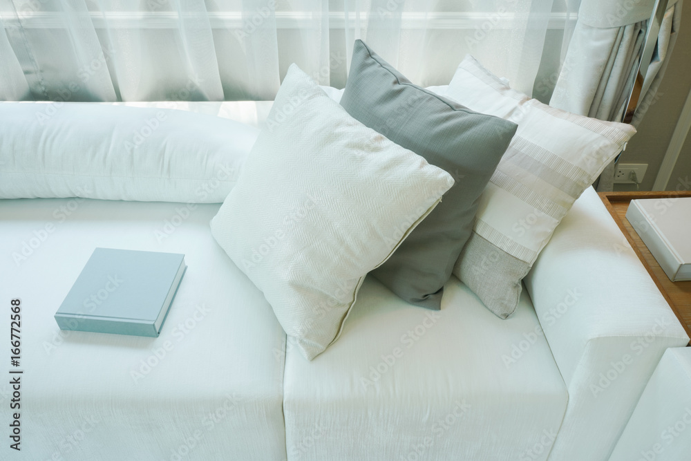 Wall mural Pillows and books setting on white sofa in living room