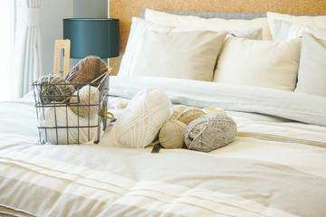 Fototapeta na wymiar Knitting wools on bed in light brown bedroom interior decoration