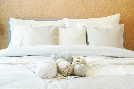 Beige color scheme bedding with knitting wools on bed