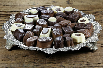 silver tray with Belgian chocolate pralines on rustic wooden background