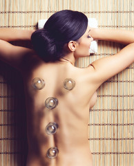 Young, beautiful and healthy woman having hot jar massage in spa. Oriental vacuum cupping concept.