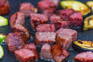 cooking slices of sausage and vegetables on the grill