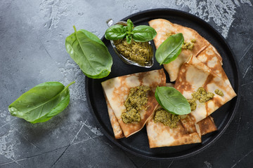 Crepes with basil pesto sauce on a metal plate, view from above, horizontal shot