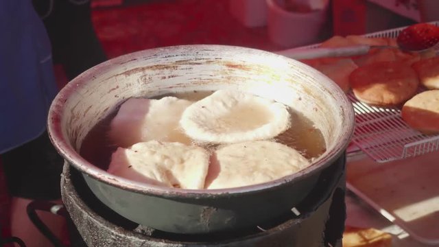 Meat pasty is being fried outside on open fire in a pot with oil
