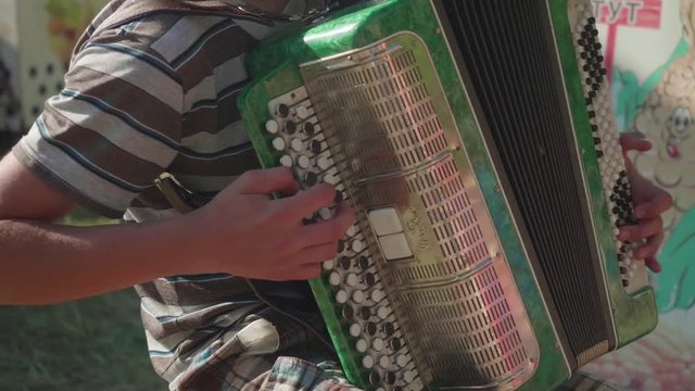 Boy playing accordion sitting on chair outdoors