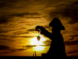 Fototapeta premium Tajemniczy latarnik na tle zachodzącego słońca