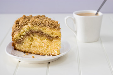 Cinnamon crumble coffee cake and cup of milk tea on white background