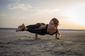 Fototapeta na wymiar young fit woman training yoga poses in desert during the sunset or sunrise, female in black sportswear do stretching exercises 