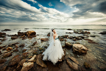 Fototapeta na wymiar Bride with a long veil for a walk by the sea