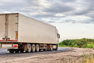 white lorry with white trailer over blue sky on the road