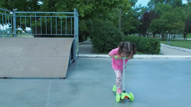 A beautiful little girl is riding a scooter. Emotion of the child on the scooter.