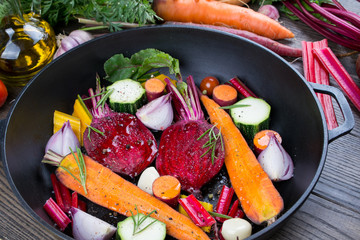 Raw sliced vegetables for roasting, on a baking tray. Assortment of vegetables from the garden. Healthy food .Carrot, beet, chard, zucchini, onion, garlic, tomato.