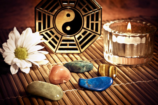 Ying yang, i-ching with healing stones, candle and a daisy flower like a concept of chinese oriental astrology 