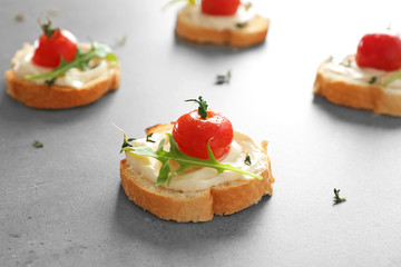 Delicious toasts with cherry tomatoes, ruccola and sauce on table