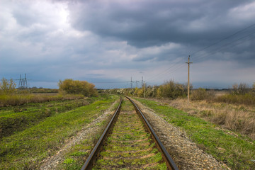 Fototapeta na wymiar railroad near high voltage power lines at dramatic sky