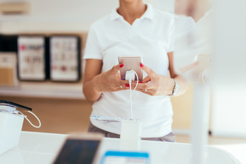 Close up shot of beautiful woman shopping. She is standing in mobile and tablet shop and choosing next model for her.