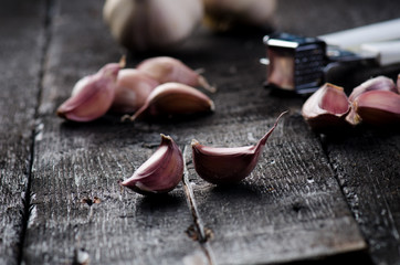 Cloves of garlic on a wooden black table. Fresh garlic bulb with iron garlic press. Vintage background.  Farmer. Medicine and healthy. Traditional medicine.