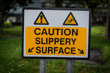 Caution slippery surface warning sign on a street