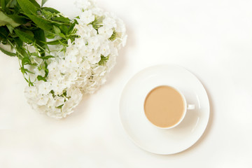 Obraz na płótnie Canvas Coffee with milk, phlox flower on white table from above. Female working desk. Hygge breakfast. Mockup. Flat lay.