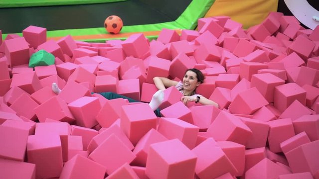 A young woman is having fun and jumping from the rope to a bright pit with a soft paralon