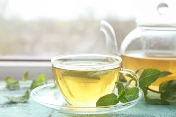 Crédence de cuisine en verre imprimé Theé Cup of hot aromatic tea with lemon balm on window sill