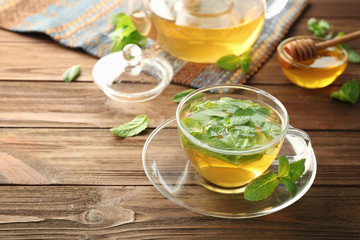 Cup of hot aromatic tea with lemon balm on wooden table