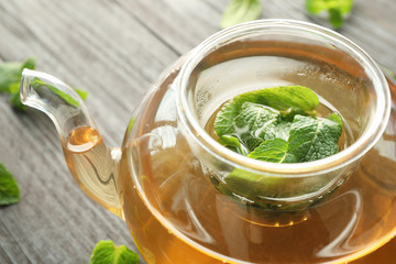 Teapot of hot aromatic tea with lemon balm on wooden table