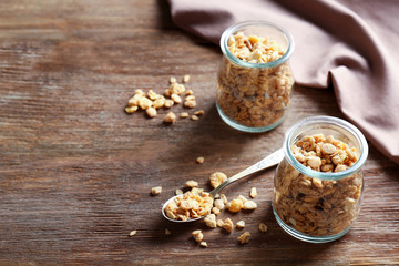 Healthy breakfast cereal in glass jars on wooden background