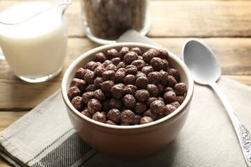 Chocolate corn balls in bowl and jug with milk on wooden table