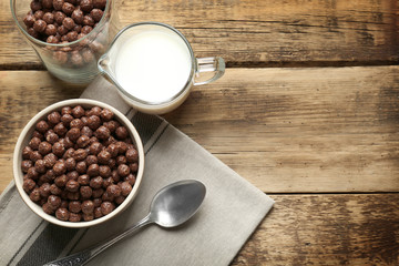 Chocolate corn balls in bowl and jug with milk on wooden table