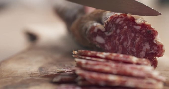 slow motion slide of female teen hand slicing dried italian salami