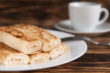 Breakfast. Pancakes on a wooden table with cheese and black currants. In the background a Cup of coffee.