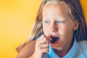 The girl lies in her mouth a juicy strawberry.