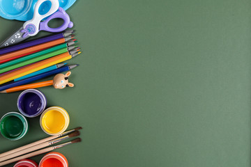 school. pencils, paints, scissors on a green school Board.